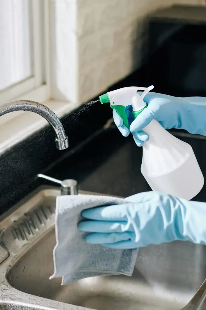 a cropped photo showing cleaning kitchen tap as part of vacate cleaning services