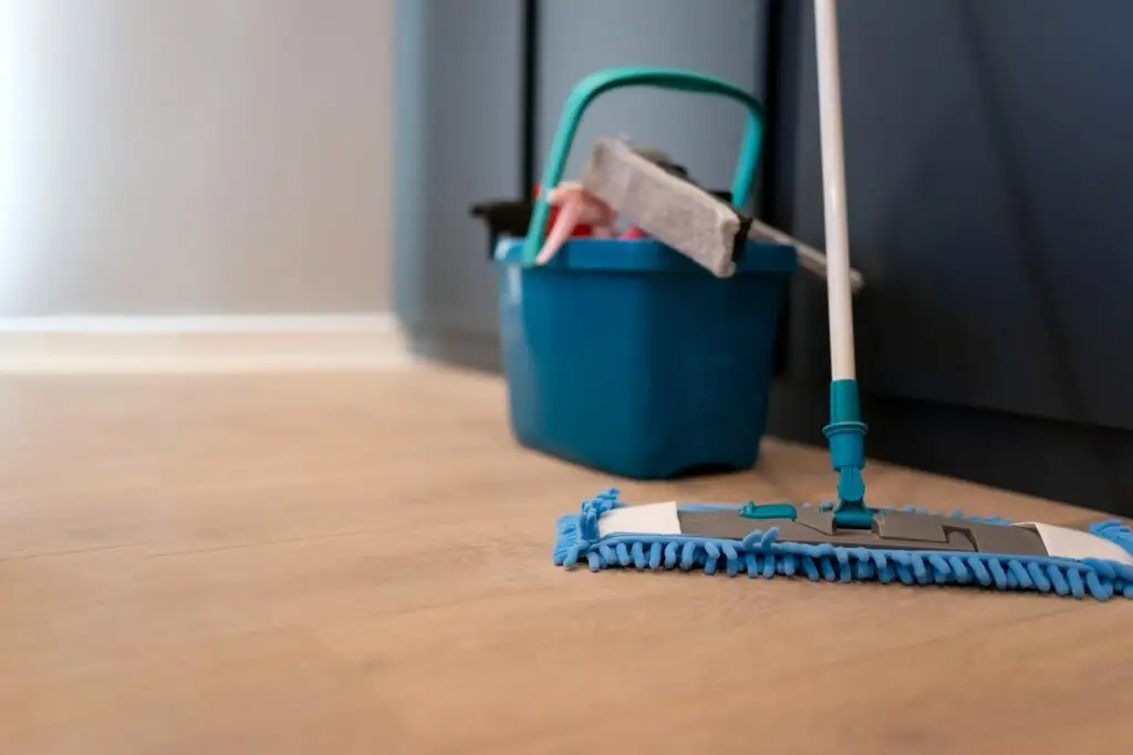 Cleaning concept. Mop and plastic bucket with cleaning products on the floor
