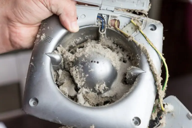 Close-up of a dusty exhaust fan held in male hands, showing visible dirt and buildup on the fan blades and grille—ideal for cleaning tutorials or maintenance guides.