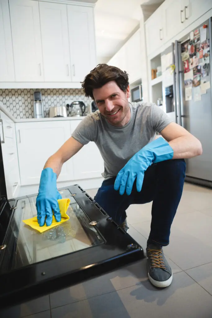 End Of Lease Oven Cleaning In Two Rocks 5 Man wearing blue gloves using yellow microfibre cloth to clean inside a gas oven during end-of-lease cleaning