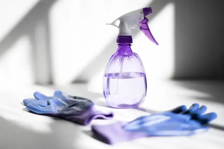 Bond Cleaning Yangebup 5 Purple spray bottle and blue cleaning gloves placed on a white surface, representing PPE and chemical tools used in bond cleaning in Perth.